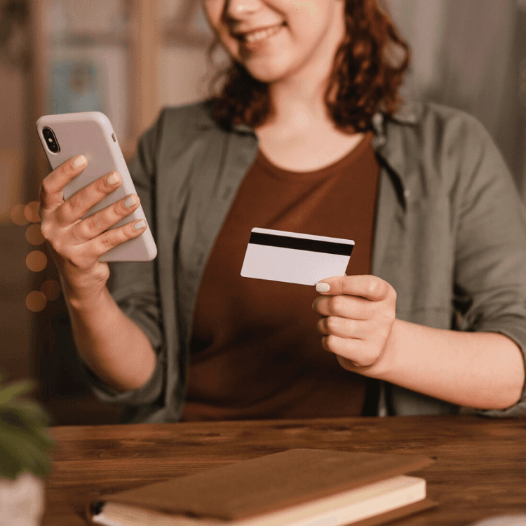 Woman holds a phone and a bankcard